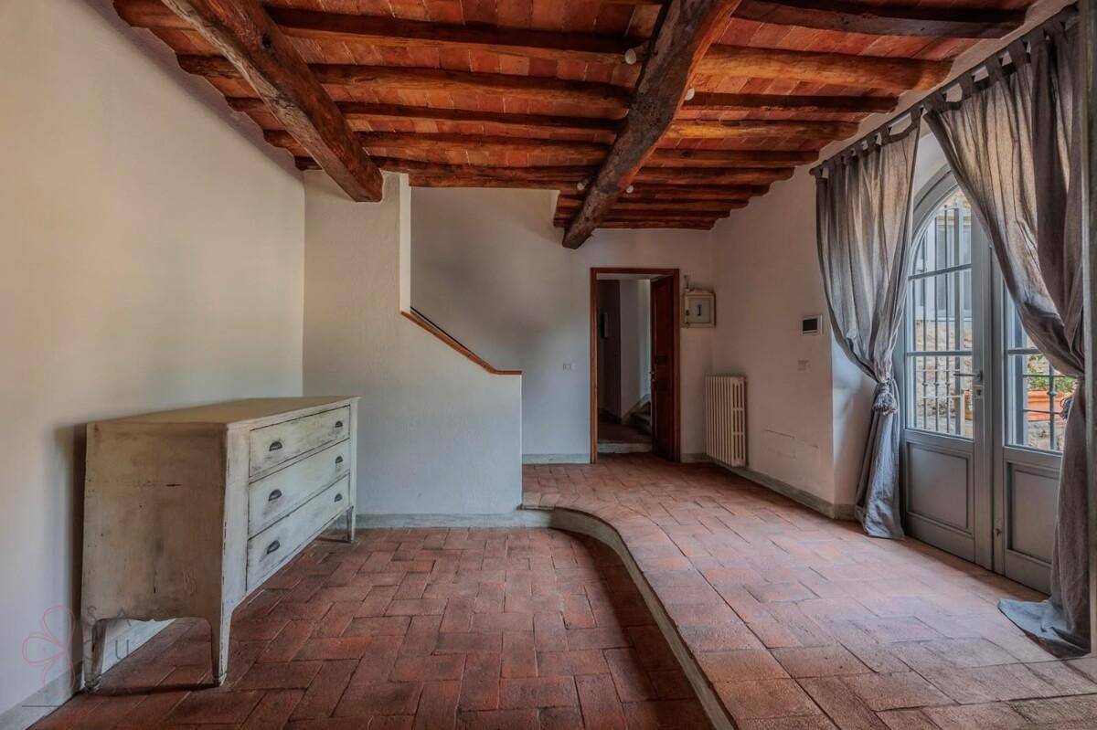 Heller Flur mit Terrakottaboden, Holzbalkendecke und einer eleganten Doppeltür mit Rundbogen.