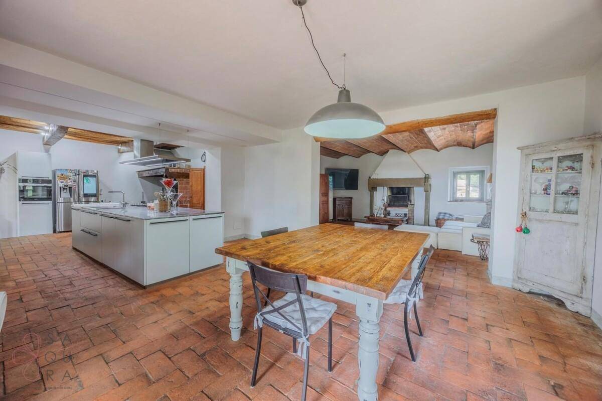 Offener Wohn- und Essbereich mit moderner Küche, Holztisch und Terrakottaboden.