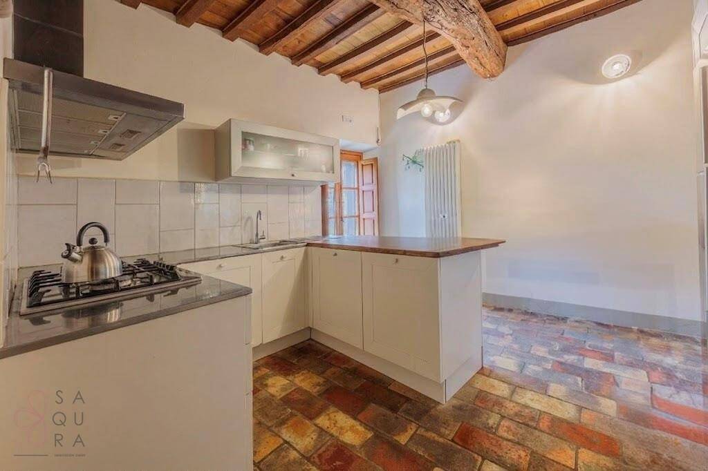 Rustikale Küche mit Terrakotta-Boden, Gasherd und Holzbalkendecke.