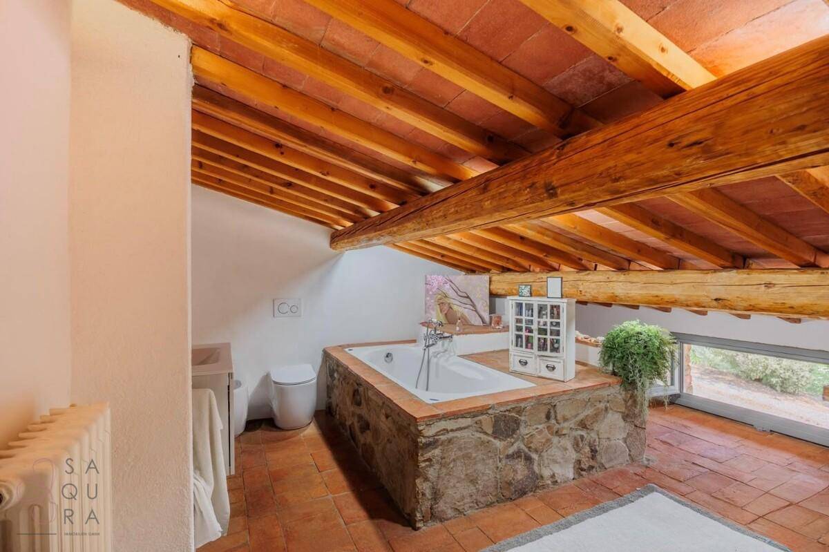 Badezimmer im Dachgeschoss mit Badewanne, Terrakottaboden und Holzbalkendecke.