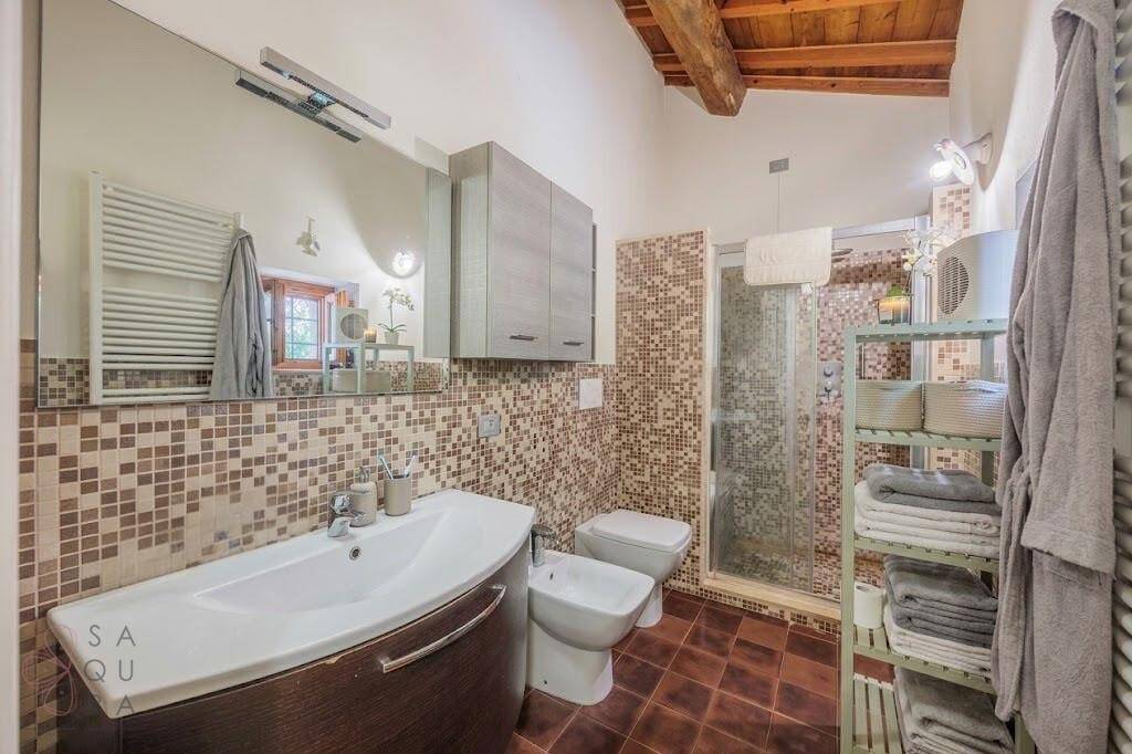 Badezimmer mit Mosaikfliesen, Dusche, Bidet und Holzbalkendecke.