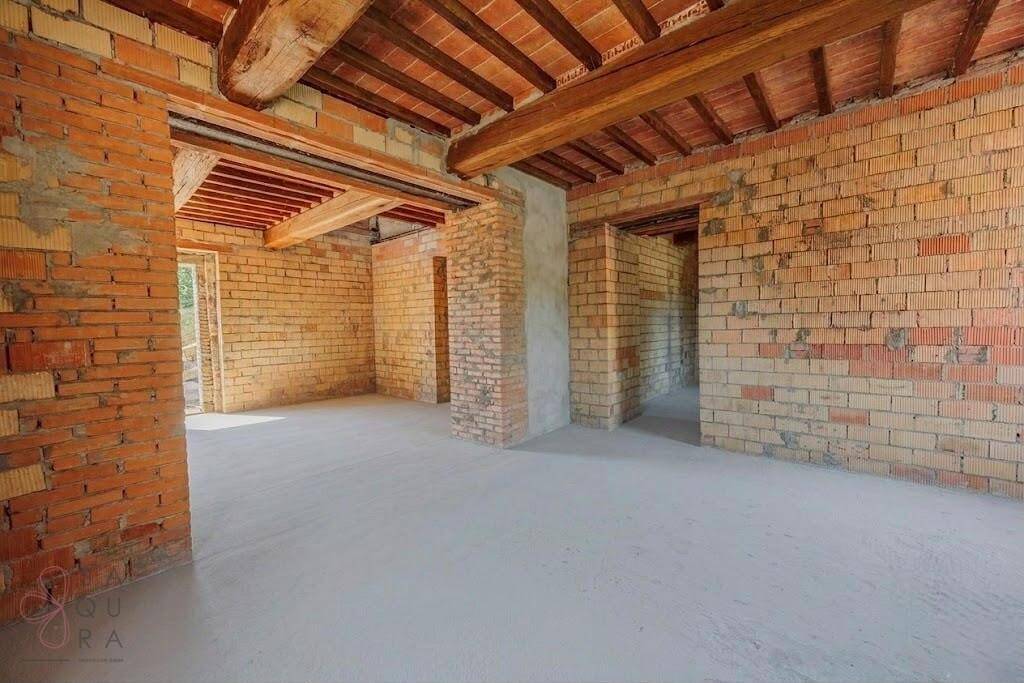 Rohbau eines Innenraums mit sichtbaren Ziegelwänden und Holzbalkendecke, bereit für den Ausbau.
