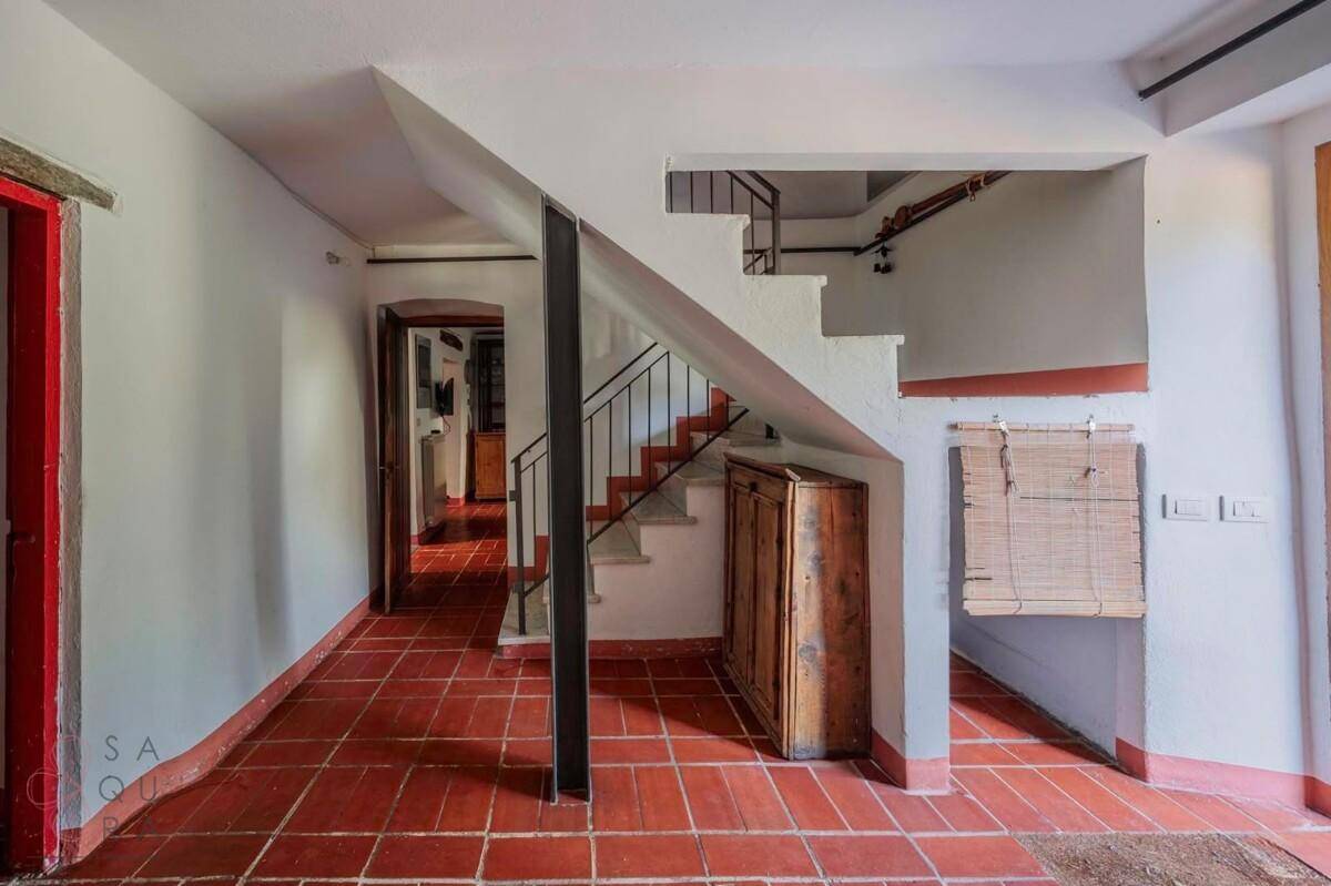 Flur mit Terrakottaboden und Treppe zum Obergeschoss, verbindet verschiedene Wohnbereiche.