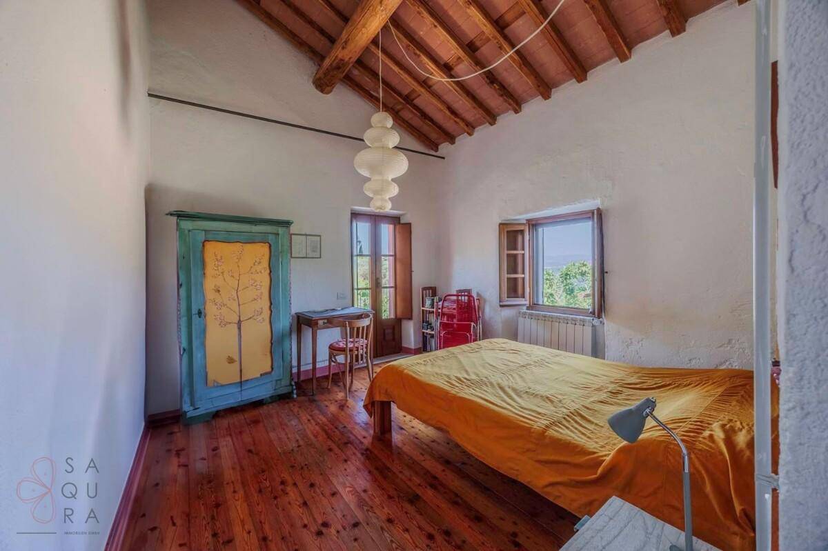 Schlafzimmer mit Holzbalkendecke, Holzboden und farbenfroher Einrichtung, bietet ländlichen Charme.