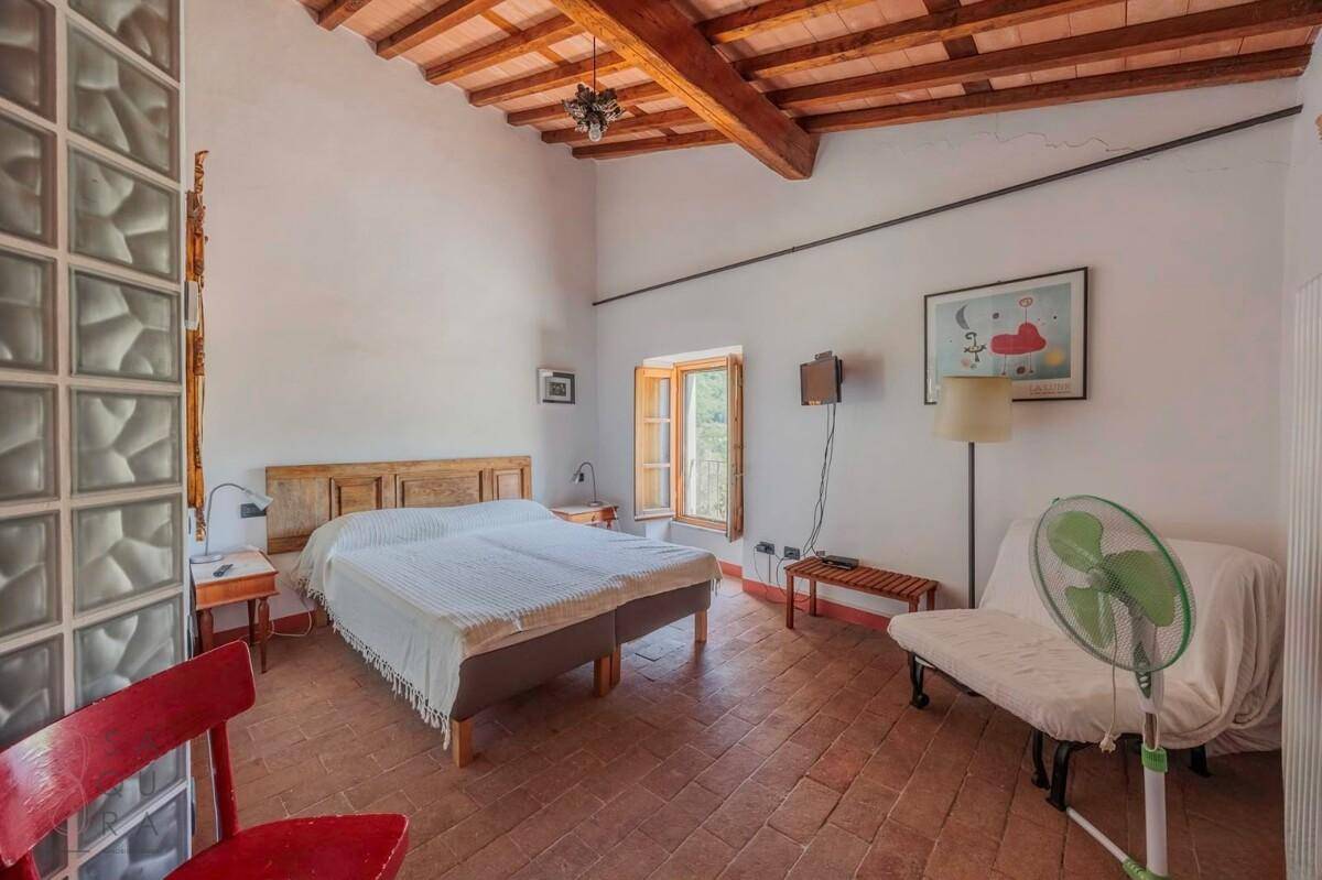 Geräumiges Schlafzimmer mit Terrakottaboden und Holzbalkendecke, bietet traditionellen Komfort.