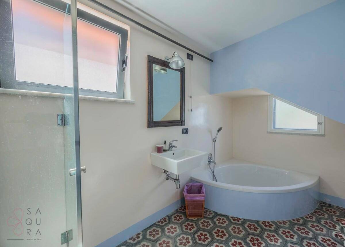 Badezimmer mit Badewanne, Waschbecken und Fenster, bietet eine entspannende Atmosphäre.