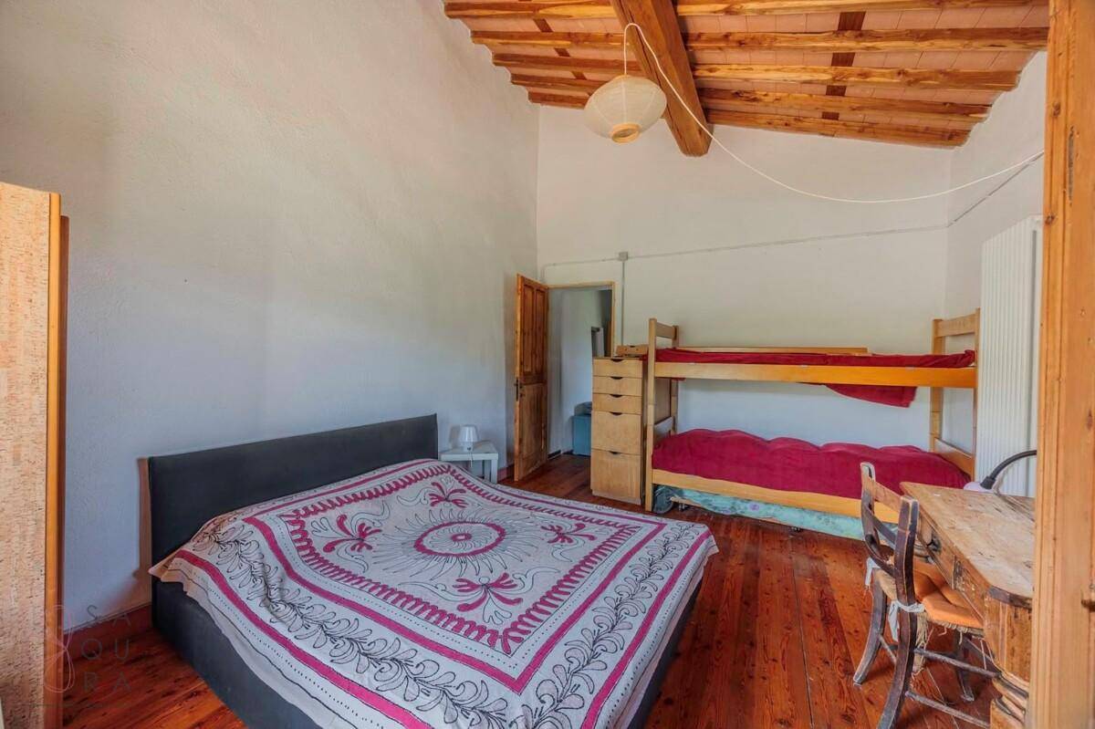 Schlafzimmer mit Holzbalkendecke, Holzboden und Etagenbett, ideal für Gäste oder Kinder.