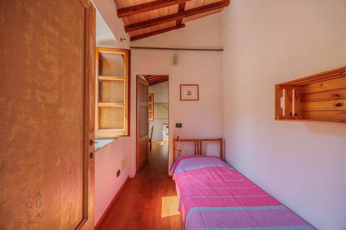 Schmaler Schlafbereich mit Holzboden und Holzbalkendecke, ideal als Einzelzimmer oder Gästezimmer.