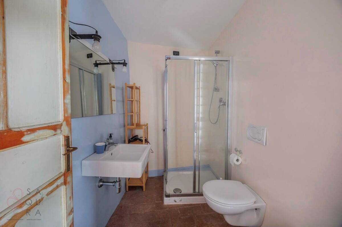 Badezimmer mit Duschkabine, Waschbecken und Toilette, funktional und hell gestaltet.