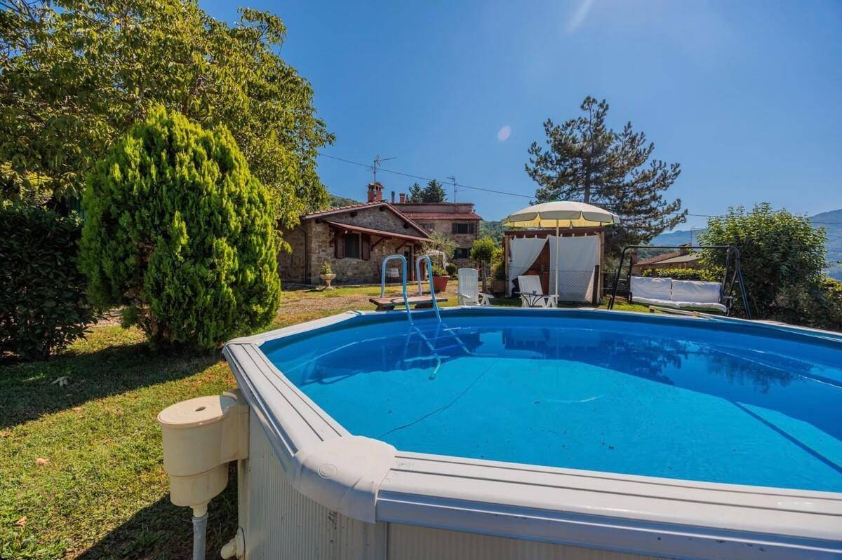 Ein oberirdischer Pool im Garten mit Blick auf die umliegende grüne Landschaft und das Haupthaus.