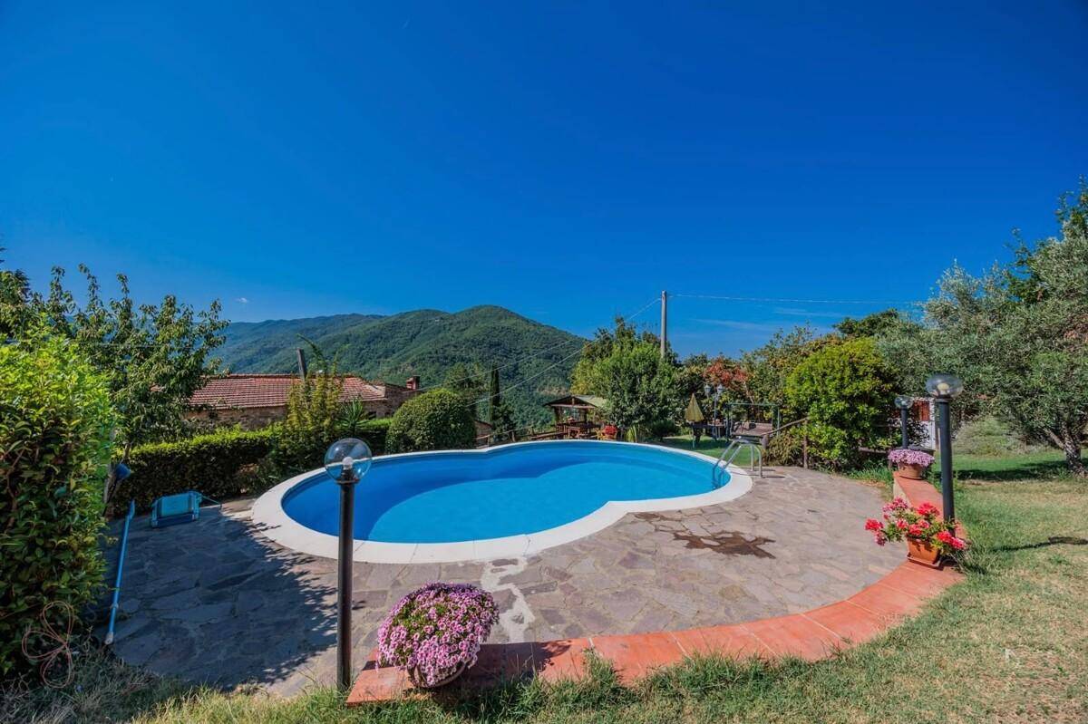 Großer Poolbereich mit Steinfliesen und üppiger Vegetation, der einen weiten Blick in die Landschaft bietet.