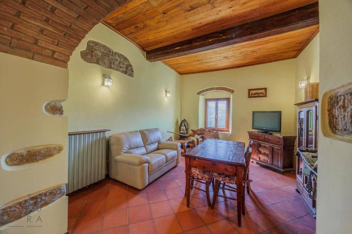 Gemütliches Wohnzimmer mit Terrakotta-Boden, Holzbalkendecke und traditionellen Möbeln.