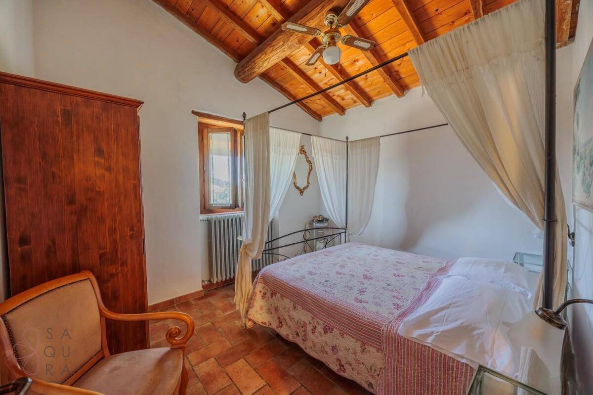 Gemütliches Schlafzimmer mit Himmelbett, Terrakotta-Boden und sichtbaren Holzbalken an der Decke.