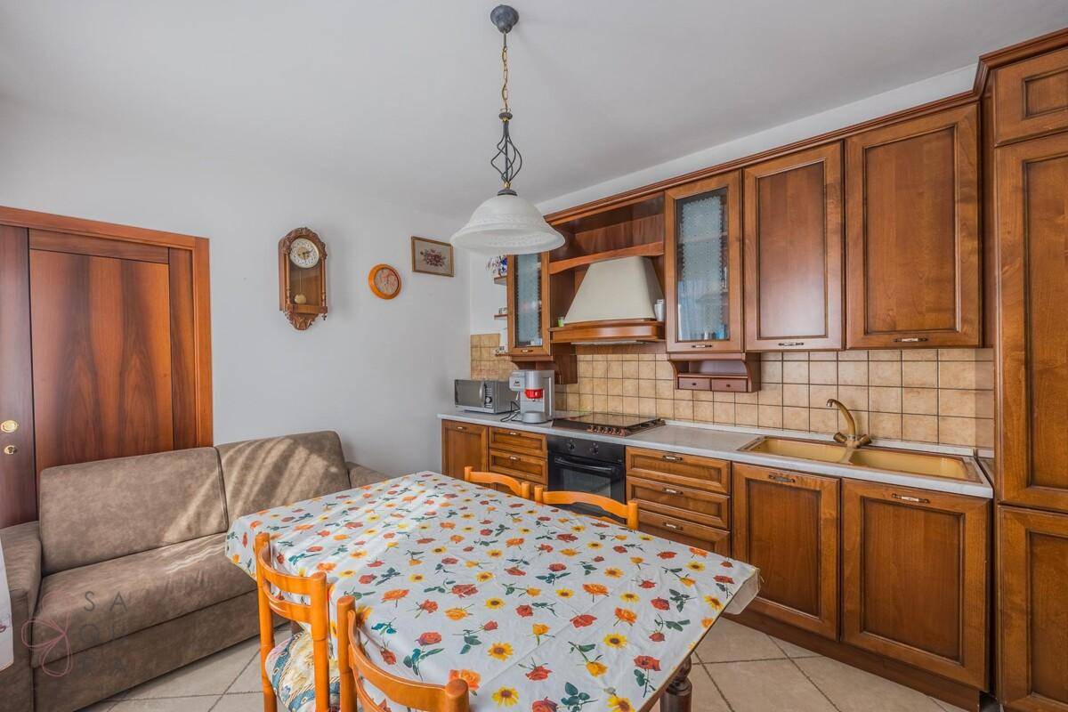 Gemütliche Wohnküche mit Holzschränken, Esstisch und einer kleinen Couch, ideal für gesellige Runden.