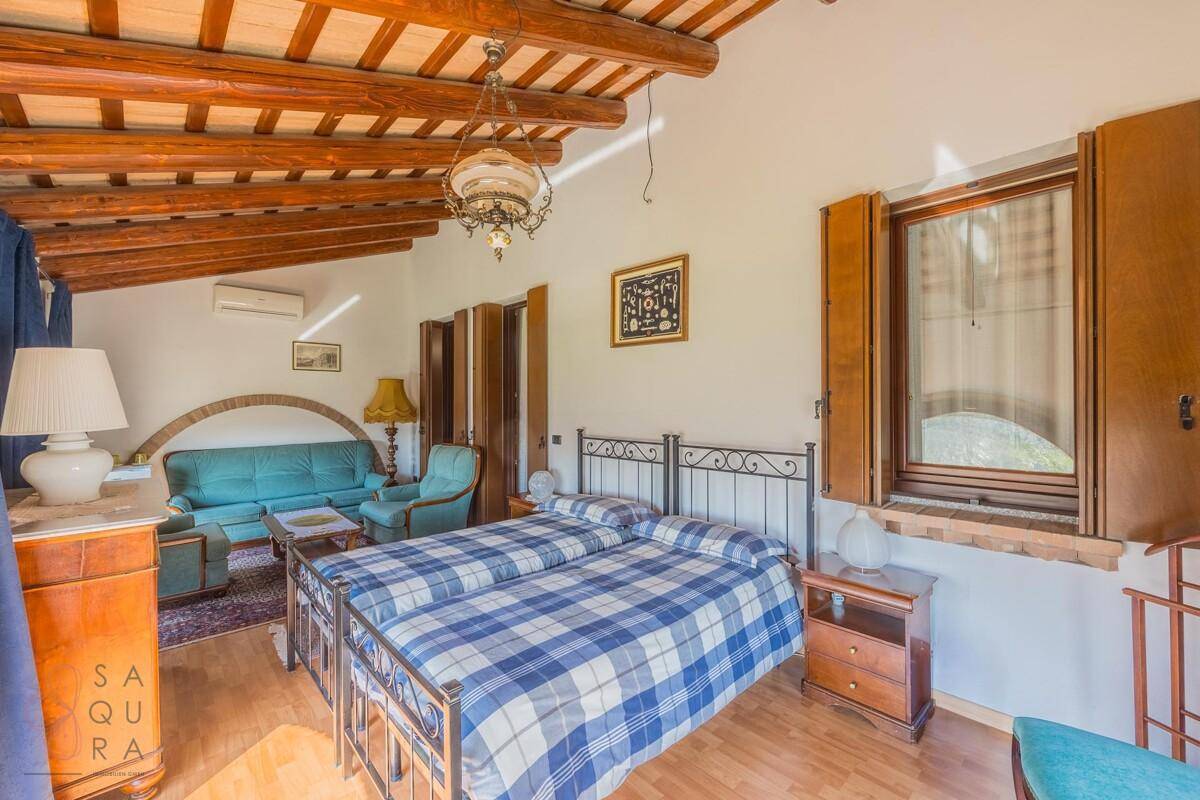 Schlafzimmer mit zwei Betten, Holzbalkendecke und gemütlicher Sitzecke unter der Dachschräge.