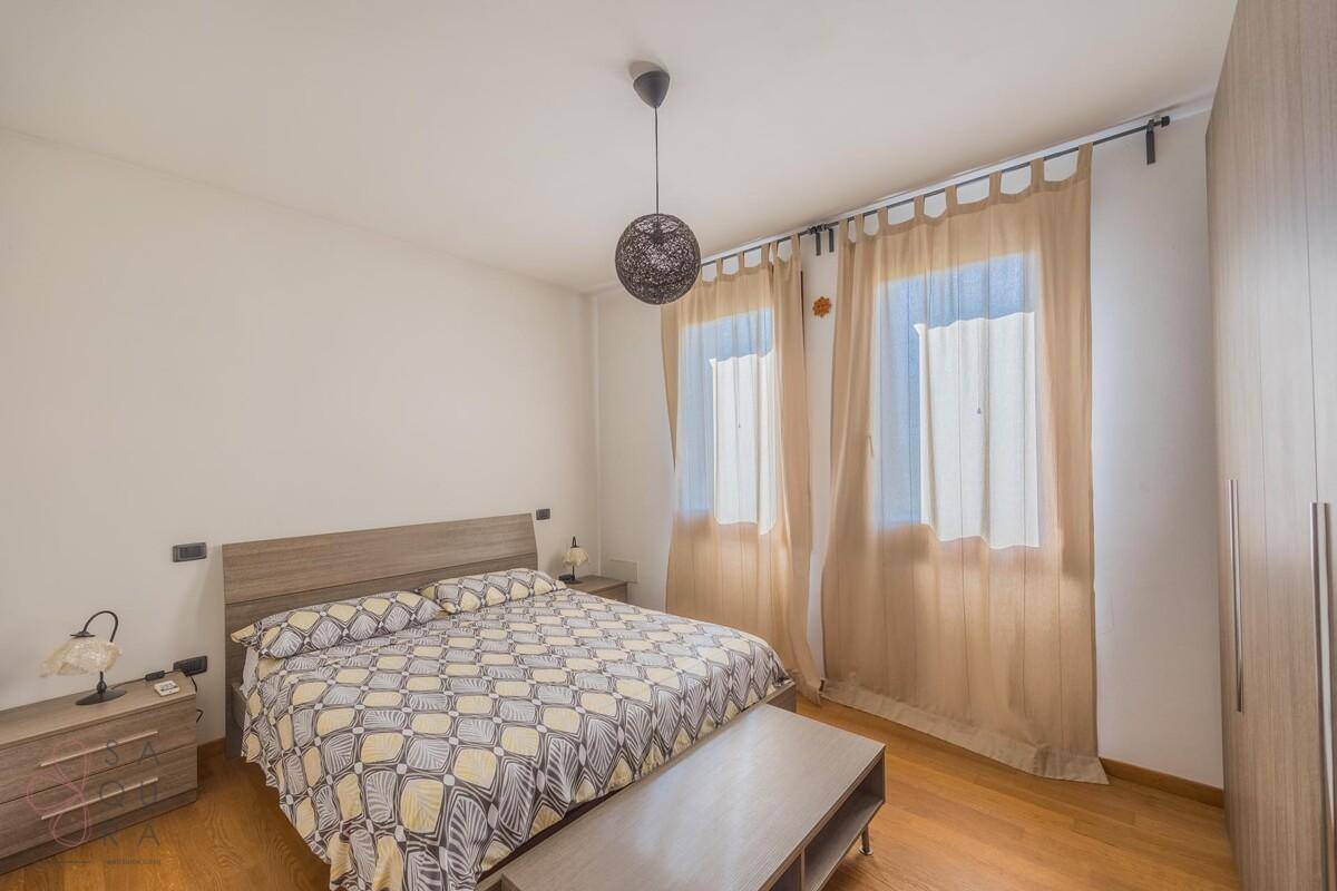 Modern eingerichtetes Schlafzimmer mit Holzboden, Doppelbett und großem Kleiderschrank.