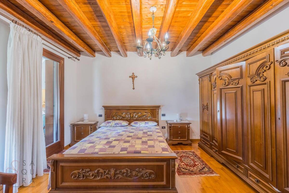 Geräumiges Schlafzimmer mit Holzbalkendecke, geschnitztem Holzbett und großem Kleiderschrank.