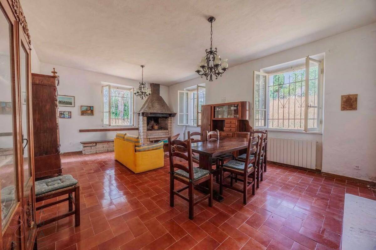 Geräumiger Wohn-Essbereich mit traditionellem Kamin, Holztisch und Terrakottafliesen.