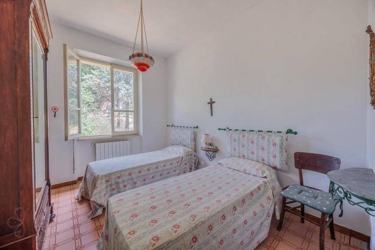 Schlafzimmer mit zwei Einzelbetten, Holzschrank und Fenster mit Blick ins Grüne.