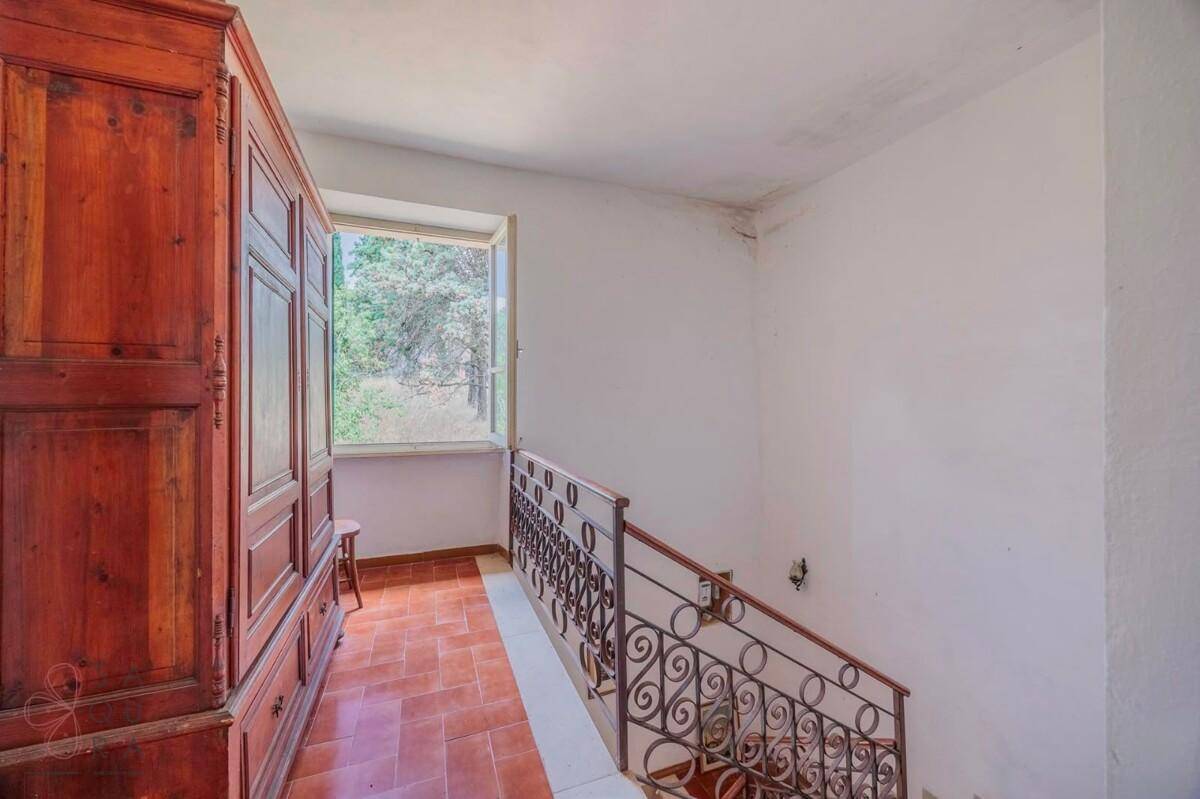 Oberer Flur mit großem Holzschrank, Terrakottafliesen und Blick auf die Treppe.