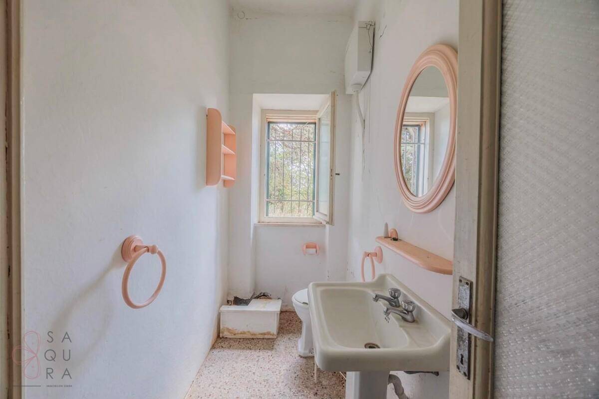 Kleines Gäste-WC mit Waschbecken, Toilette und Fenster für natürliche Belüftung.