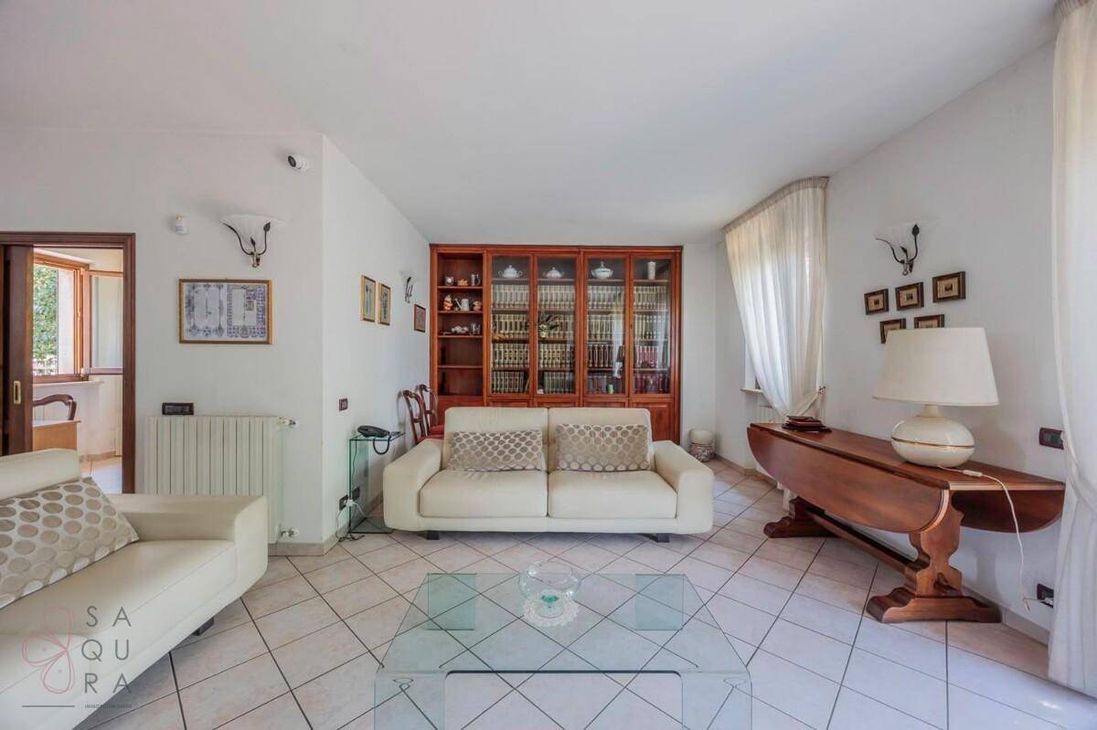 Geräumiges Wohnzimmer mit traditionellen Möbeln, Fliesenboden und viel Tageslicht.