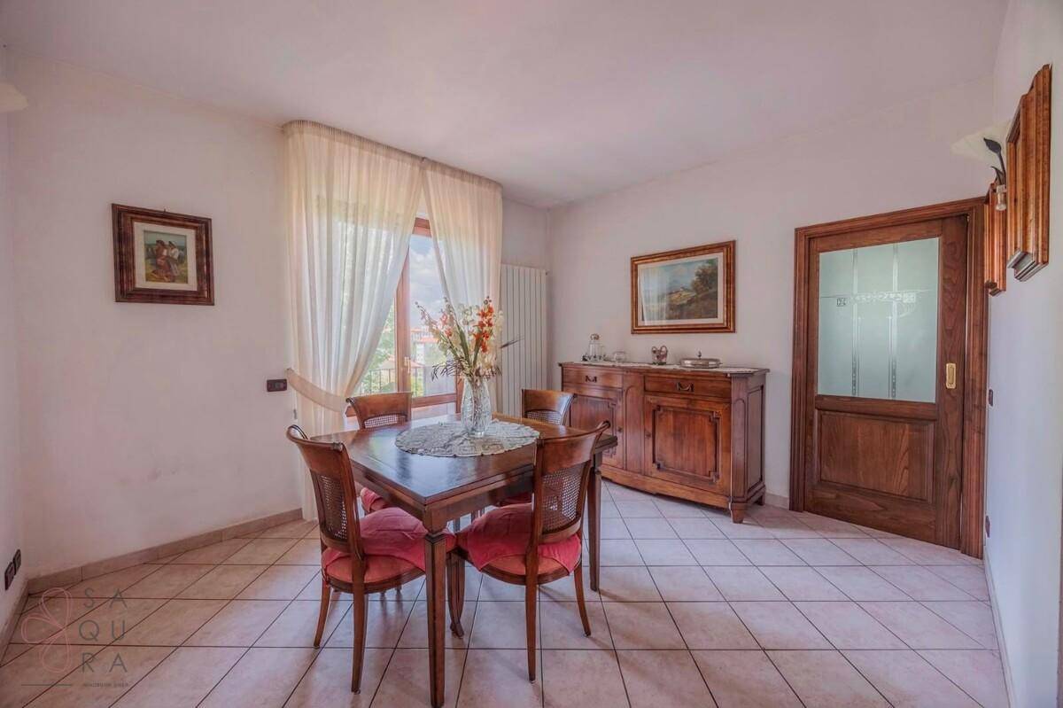 Esszimmer mit Holztisch, Stühlen, Sideboard und Fliesenboden.