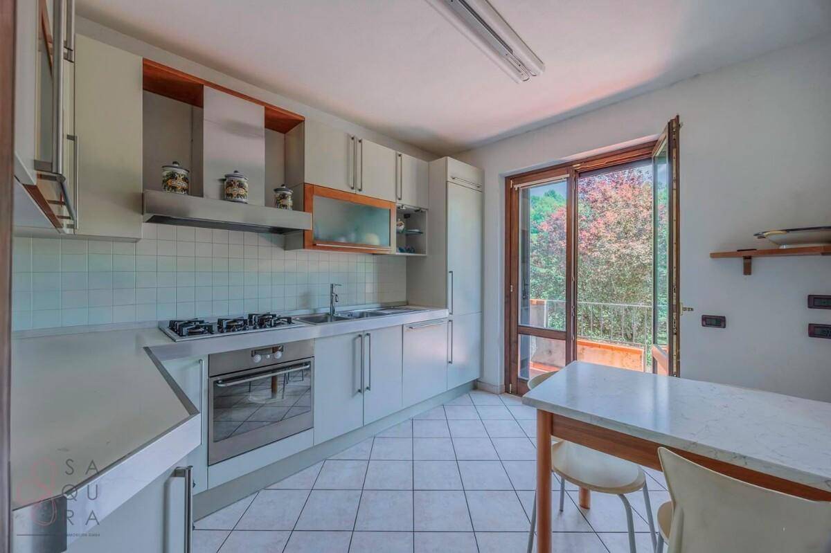 Funktionale Küche mit hellen Schränken, Gasherd und Zugang zu einem Balkon.