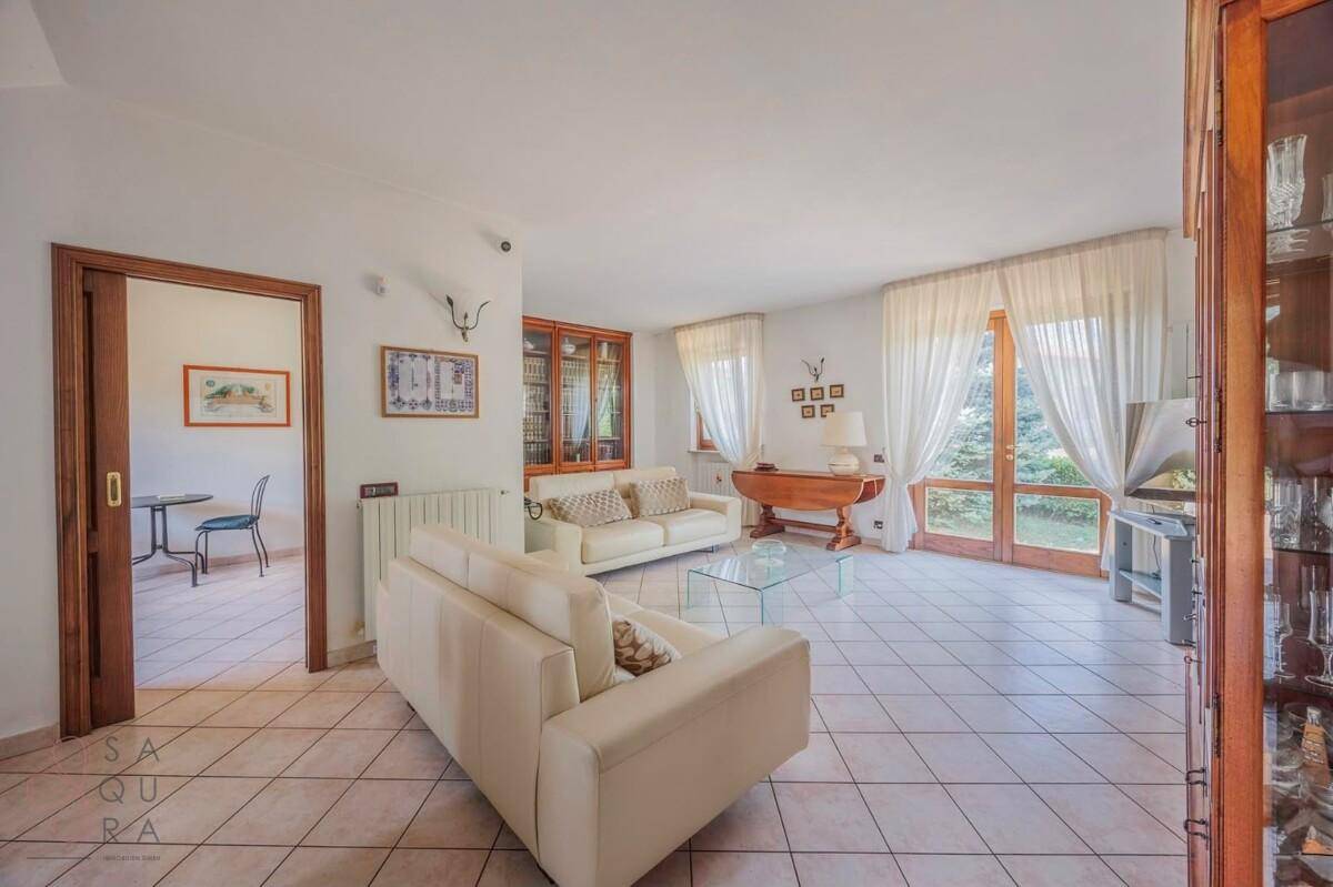Helles Wohnzimmer mit hellen Fliesen, bequemen Sofas und Zugang zum Garten.