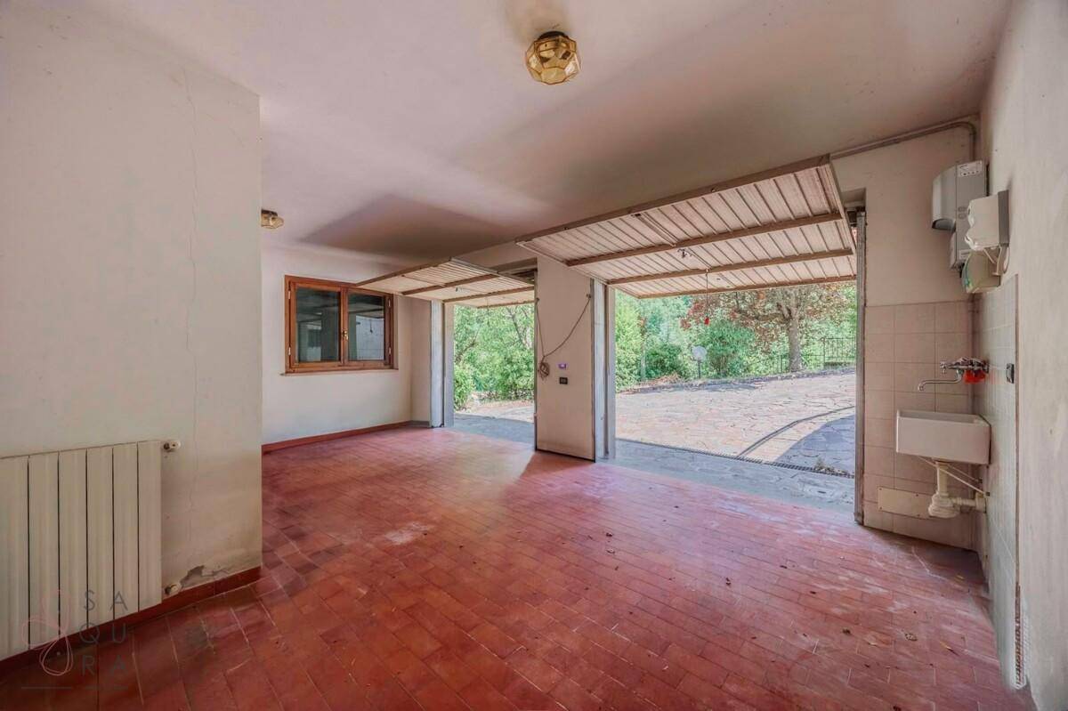 Geräumige Garage mit Fliesenboden, Fenster und Zugang zum Außenbereich.