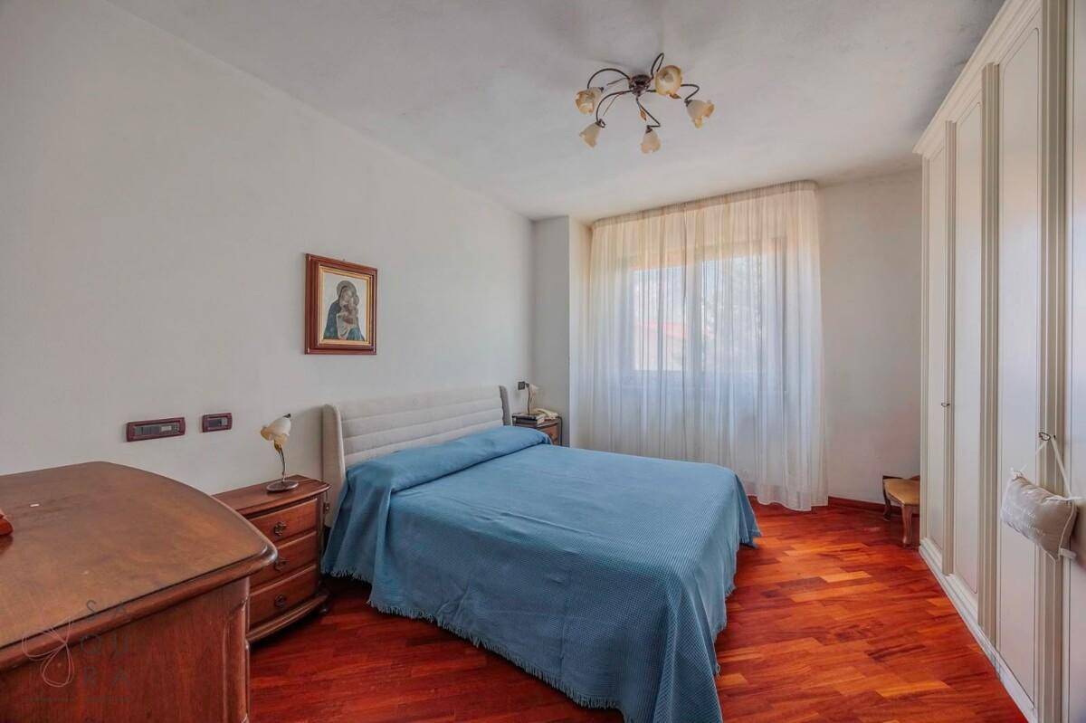 Schlafzimmer mit Holzboden, Einbauschränken und großem Fenster.