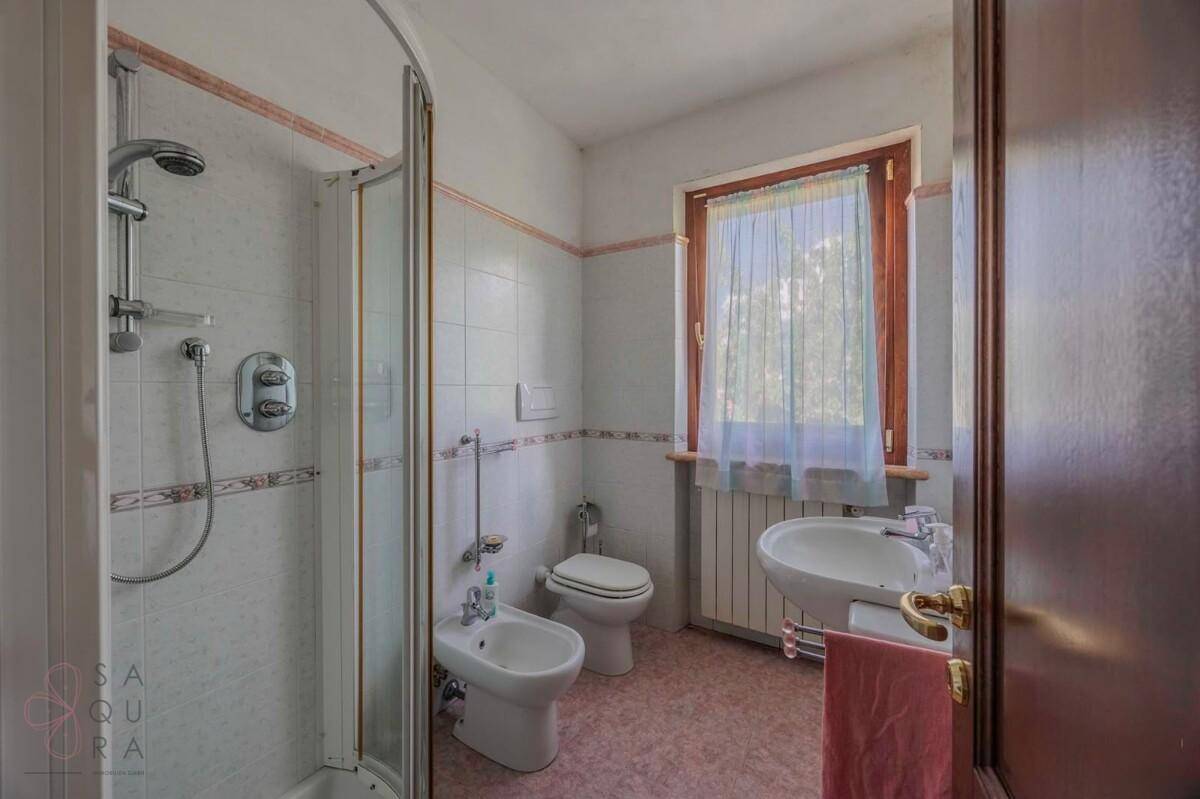 Badezimmer mit Duschkabine, Bidet, Toilette und Fenster.
