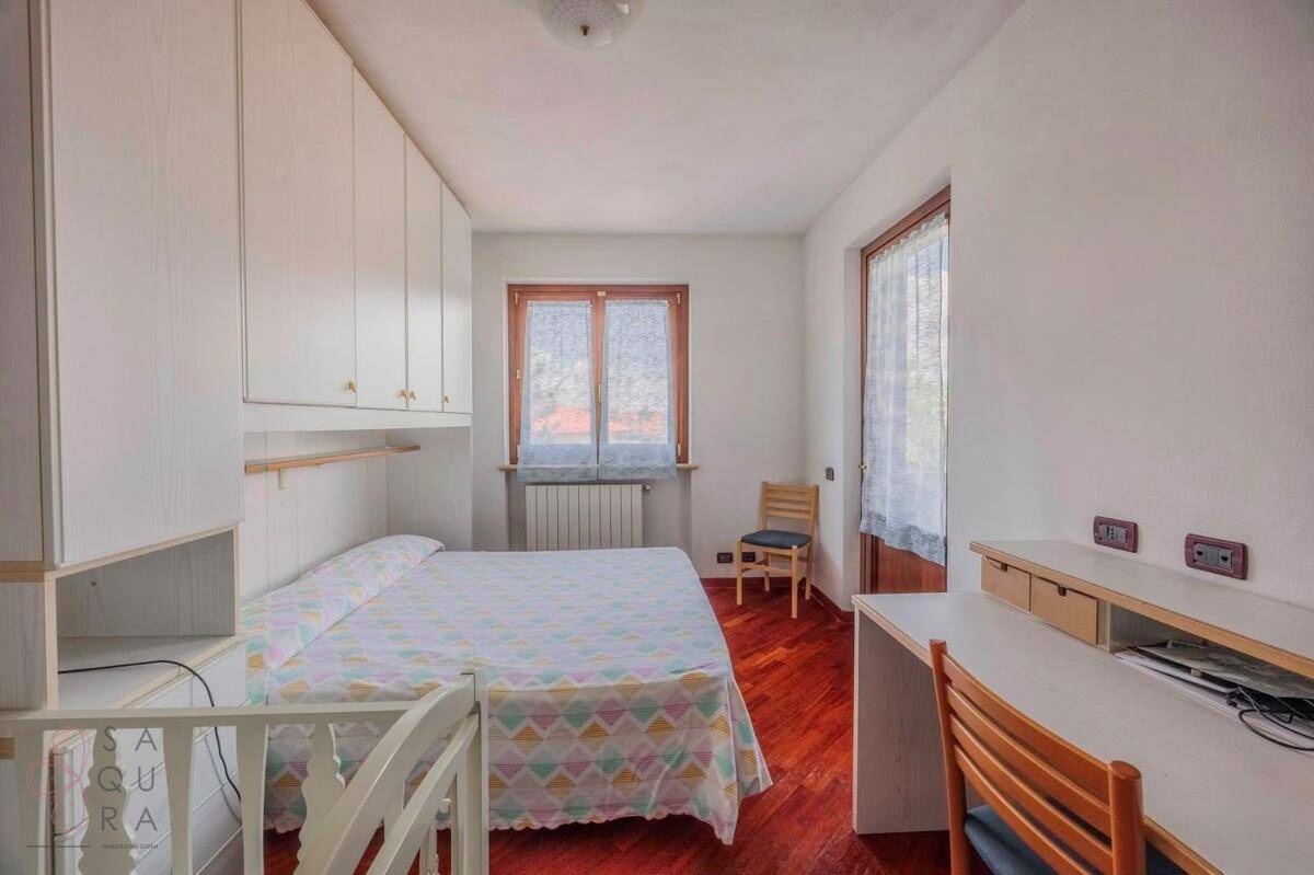 Helles Schlafzimmer mit Holzboden, Einbauschränken und Schreibtisch.