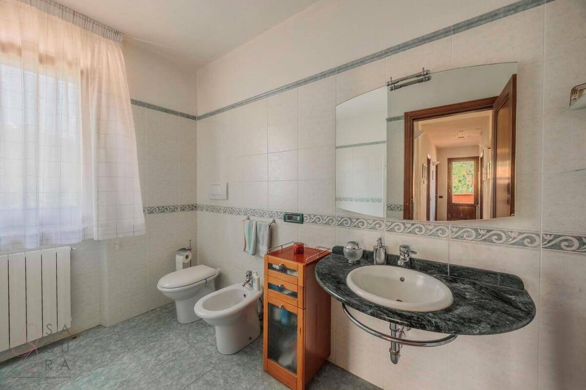 Badezimmer mit Marmorwaschtisch, Bidet, Toilette und Fenster.