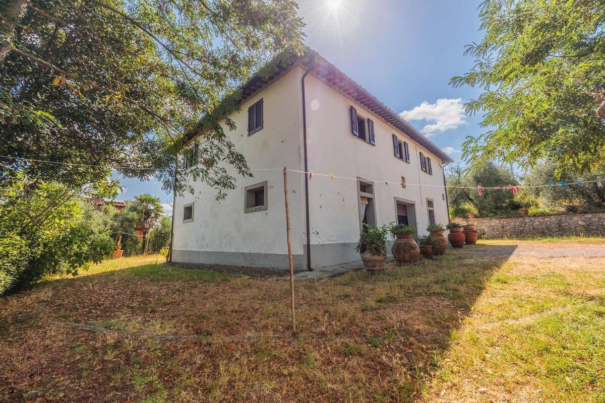 Seitenansicht des Landhauses mit Wäscheleine und sonnigem Gartenbereich.
