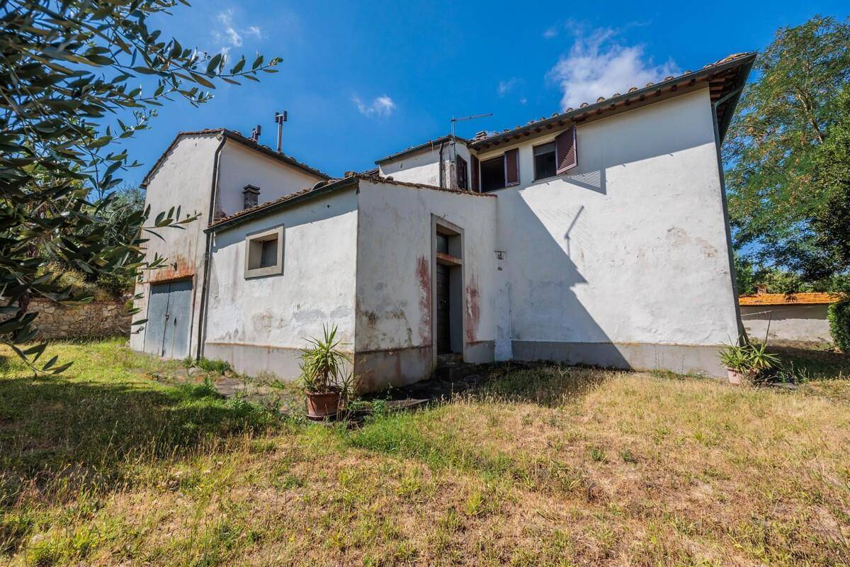 Rückansicht des Landhauses mit Anbau und Gartenfläche, die zum Haus führt.
