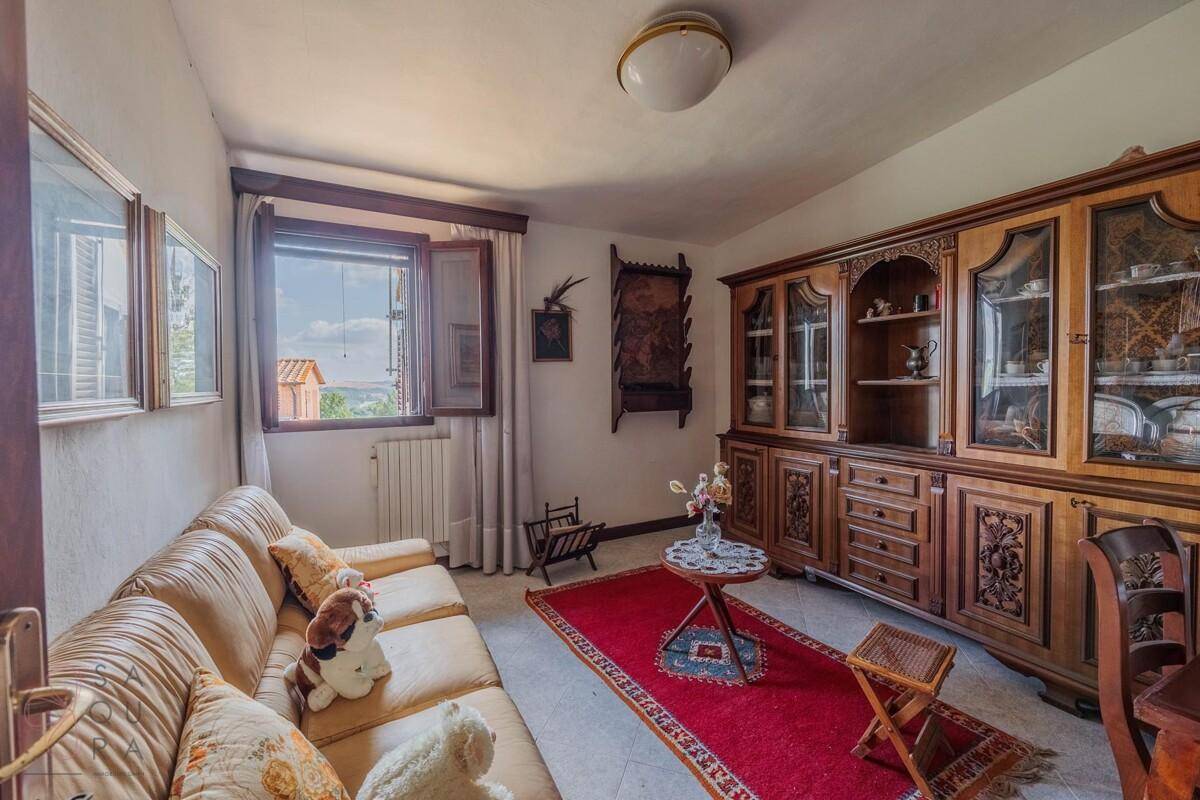 Traditionelles Wohnzimmer mit beiger Couch, rotem Teppich und antiken Holzmöbeln.