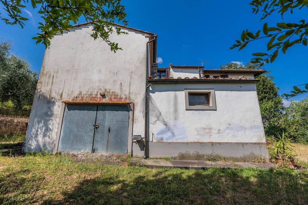 Seitenansicht des Landhauses mit blauer Garagentür und kleinem Fenster im Anbau.