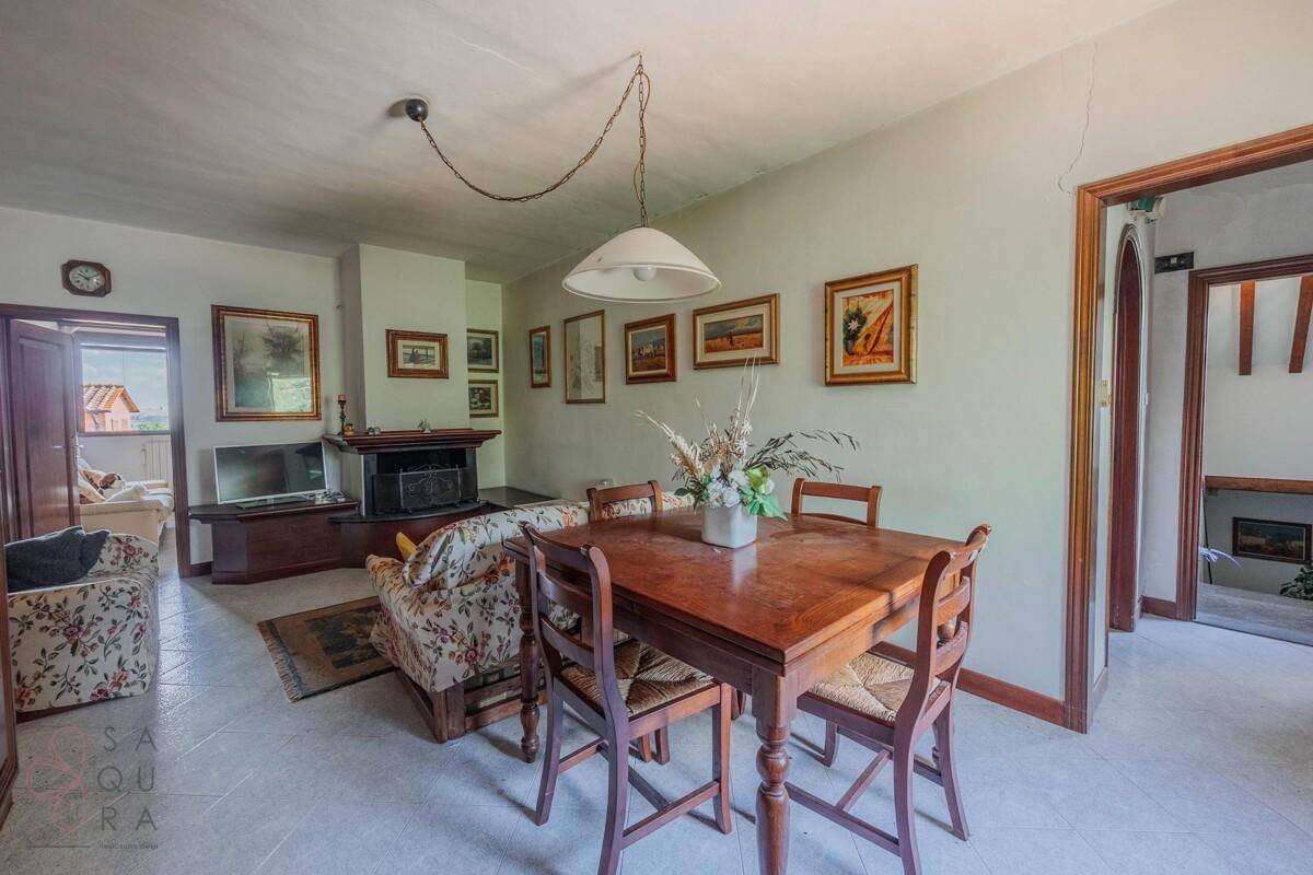 Gemütlicher Wohn-Essbereich mit Kamin, Esstisch und floral gemusterten Sofas.