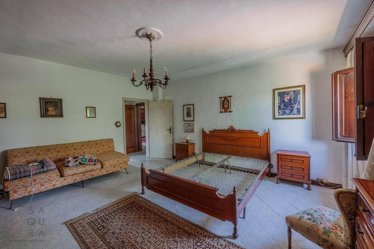Helles Schlafzimmer mit klassischem Holzbett, Sofa und Blick auf die umliegende Landschaft.