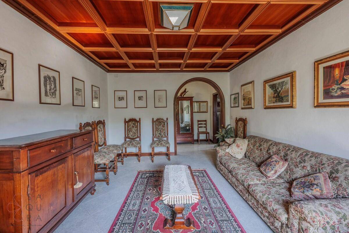 Wohnzimmer mit Holzkassettendecke, klassischem Sofa und einem Durchgang zum Flur.