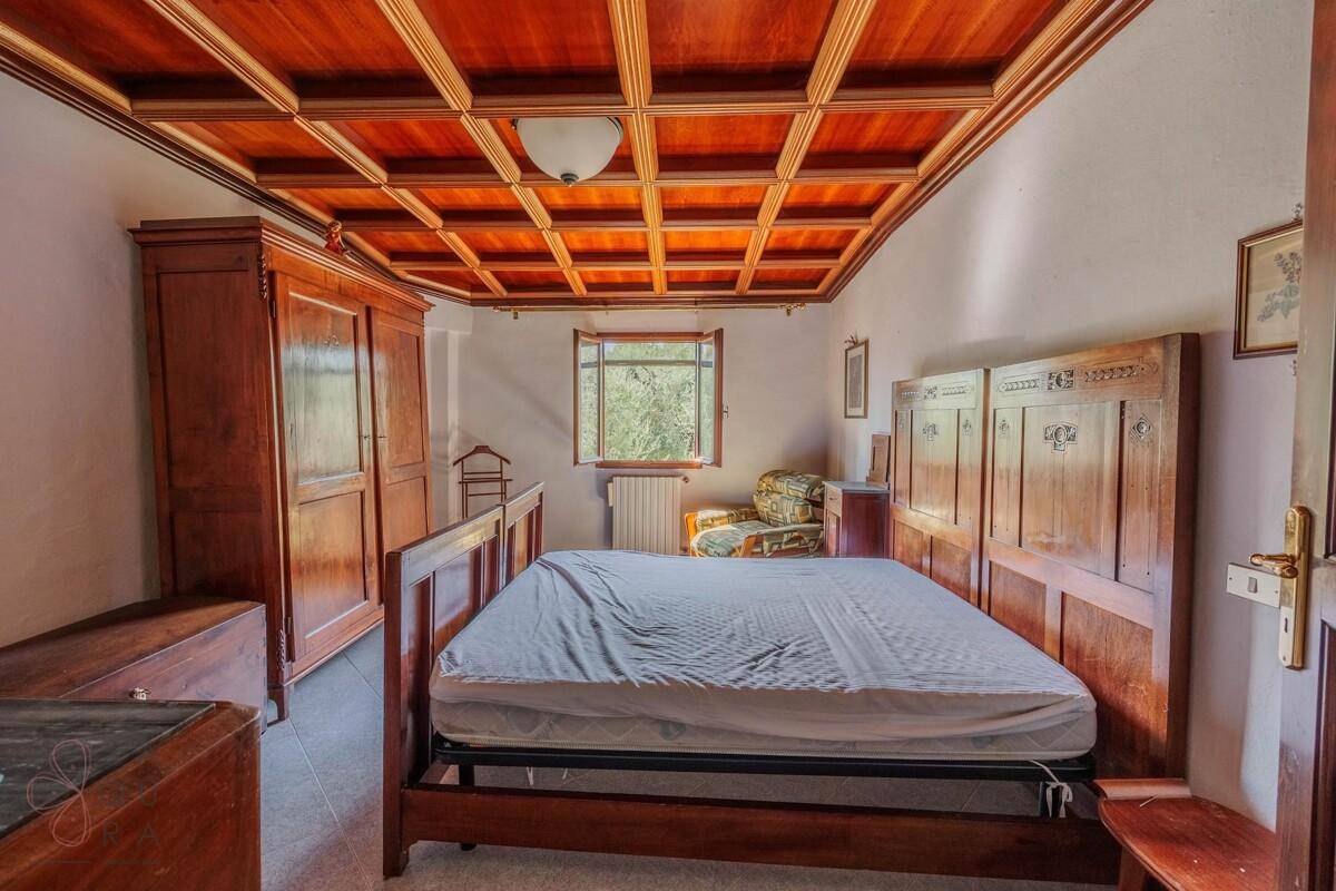 Schlafzimmer mit Holzkassettendecke, großem Holzbett und einem Kleiderschrank.