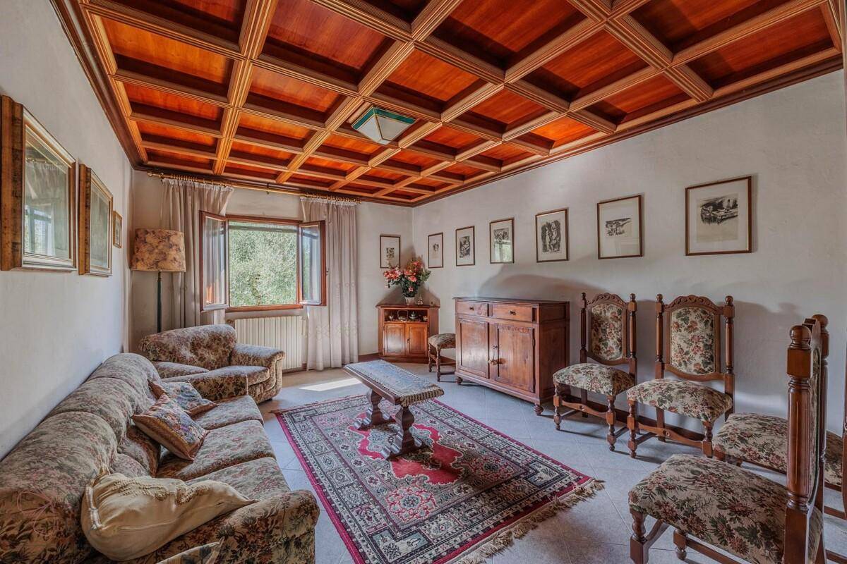 Geräumiges Wohnzimmer mit Holzkassettendecke, bequemen Sofas und einem großen Teppich.