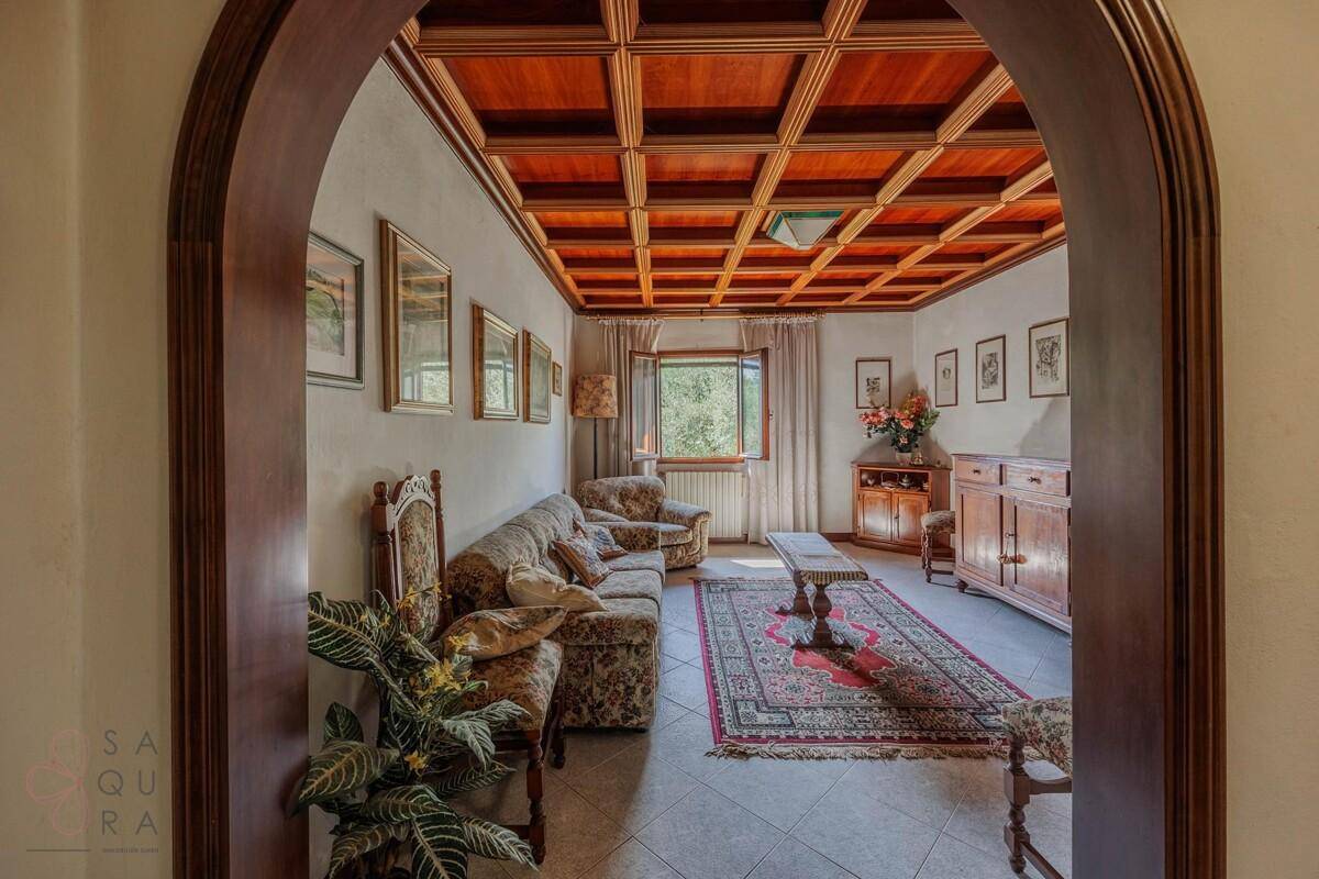 Wohnzimmer mit Holzkassettendecke, traditionellen Möbeln und Blick ins Grüne.