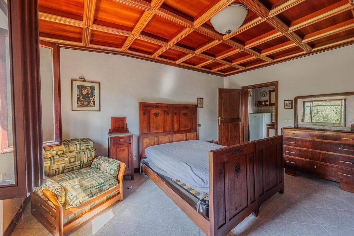 Helles Schlafzimmer mit Holzkassettendecke, Doppelbett und einer Kommode.