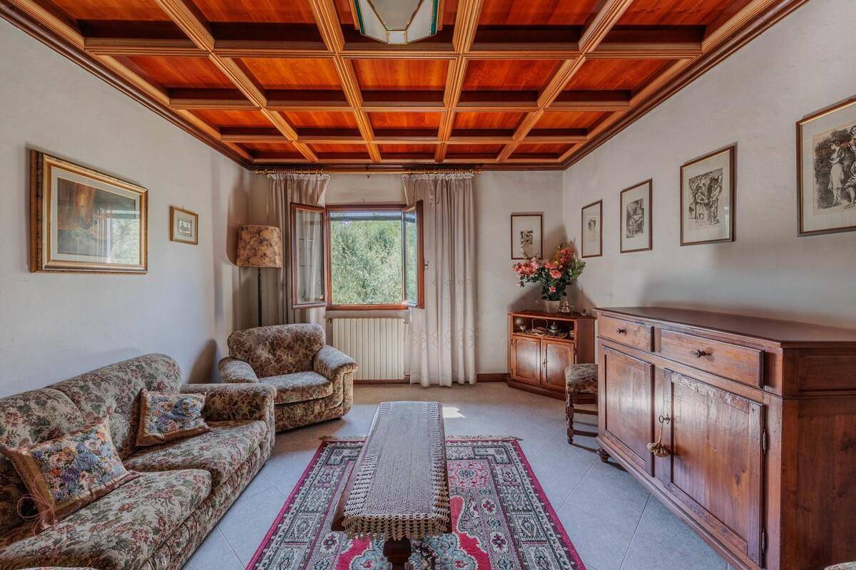 Helles Wohnzimmer mit Holzkassettendecke, traditionellen Holzmöbeln und einem Fenster.