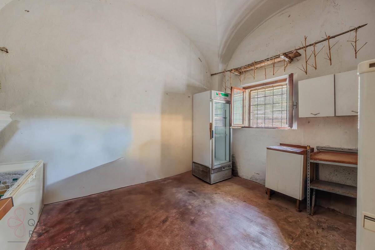 Einfacher Abstellraum mit gewölbter Decke, zwei Kühlschränken und einem kleinen Fenster.
