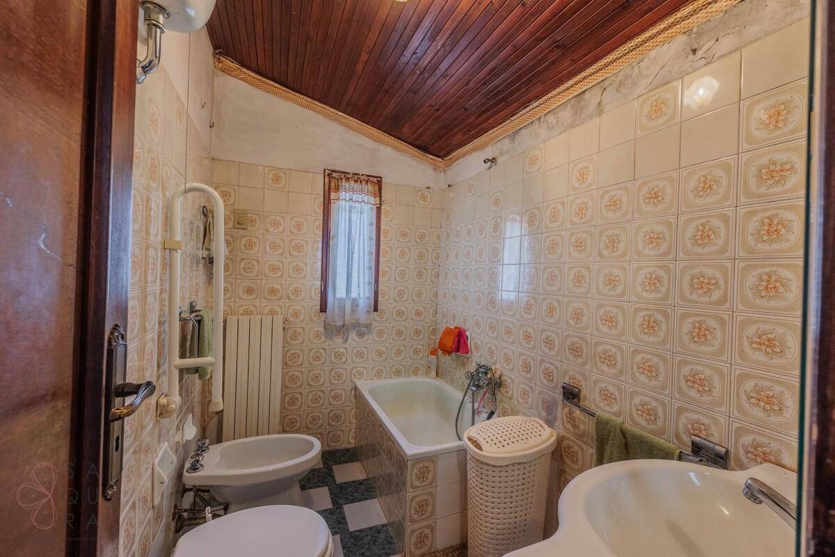 Traditionelles Badezimmer mit gemusterten Fliesen, Badewanne, Bidet und Holzdachschräge.