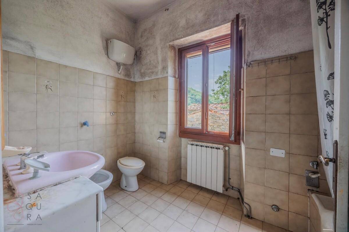 Badezimmer mit rosa Badewanne, Bidet und Fliesenboden, renovierungsbedürftig mit Fensterblick.