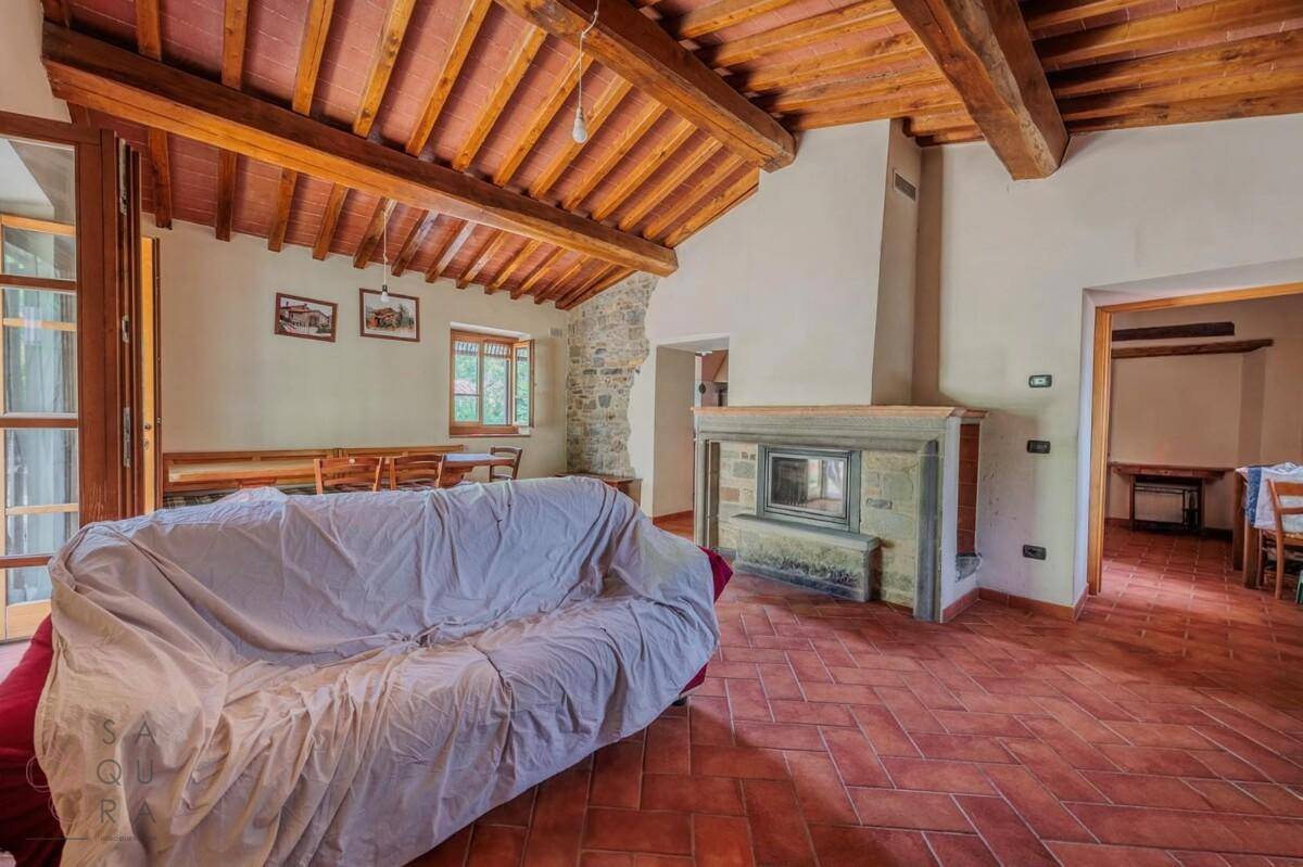 Rustikales Wohnzimmer mit Holzbalkendecke, Terrakottaboden und einem traditionellen Kamin.